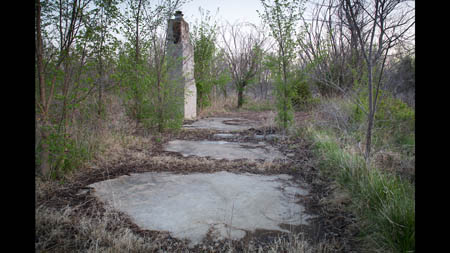 A chimney remains standing above an empty slab on the north side of Picher.