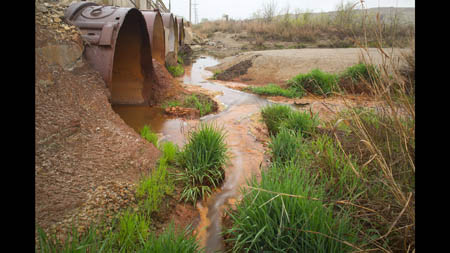 Ground water from the Boone Aquifer flows into Tar Creek after emerging rust-colored and carrying heavy metals from a collapsed mine and test holes in Picher. The Tar Creek Superfund site was designated in 1983.