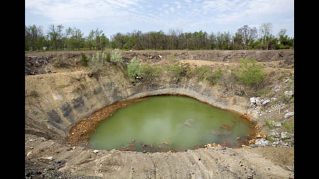 Tires float with other junk in a pond formed by a collapsed mine outside Picher. Before the ground at this spot collapsed into the cavern below, leaving a 250-foot wide hole, there were three mine shafts visible at the surface, each with a five-by-seven-foot opening. The threat of more such collapses eventually prompted the government to offer buyouts to Picher residents.